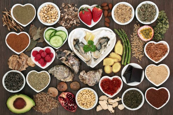 Different foods and spices in an assortment of circular and heart-shaped bowls on faux wood background