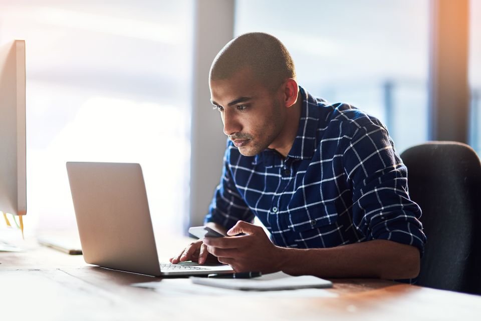 bald man in blue plaid button up searching on computer